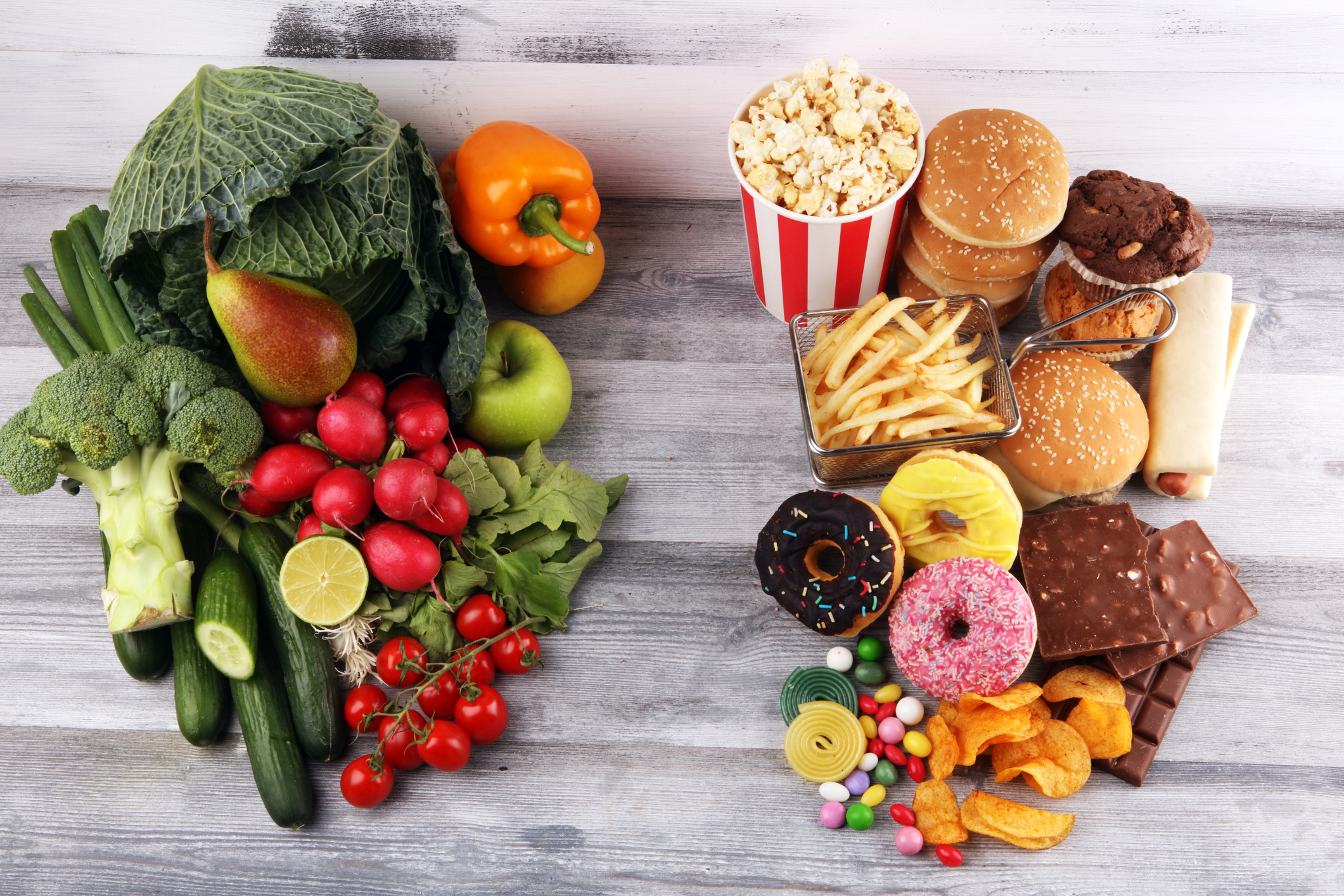 gesundes oder ungesundes Essen. Konzeptfoto von gesundem und ungesundem Essen. Obst und Gemüse vs Donuts, Süßigkeiten und Burger auf dunkel