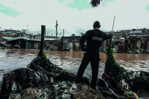 Mann blickt auf Wasserfluten inmitten eines Slums