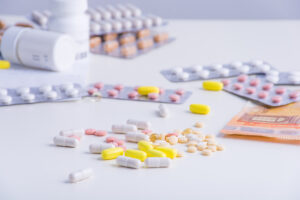 Tabletten, Pillenblister und Geldscheine liegen auf Tisch