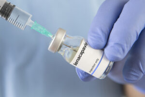 HIV-Spritze wird aufgezogen in blauen Handschuhen
