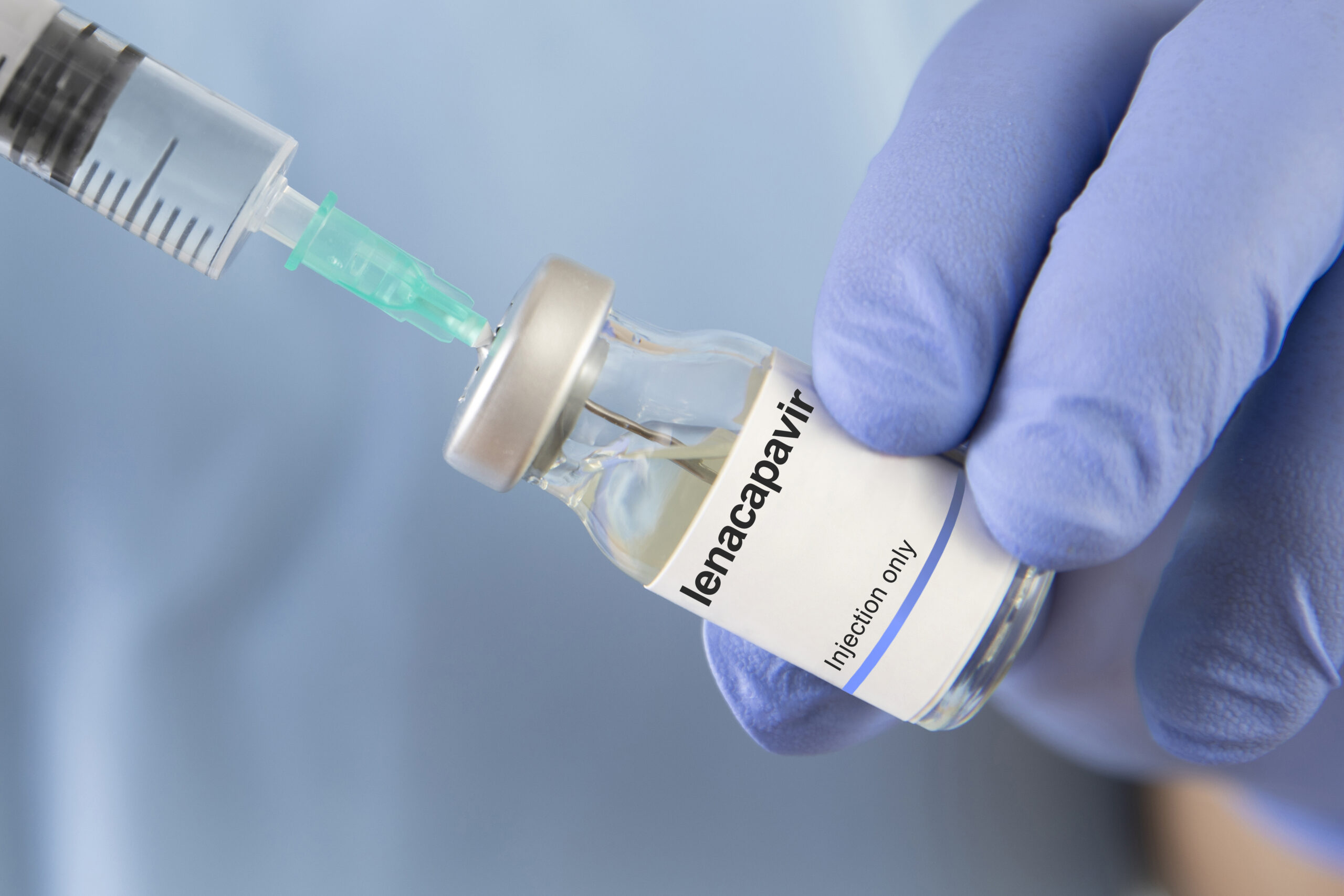 HIV-Spritze wird aufgezogen in blauen Handschuhen