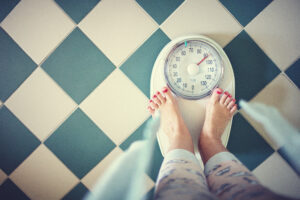 Eine Frau steht morgens im Badezimmer auf einer Waage.