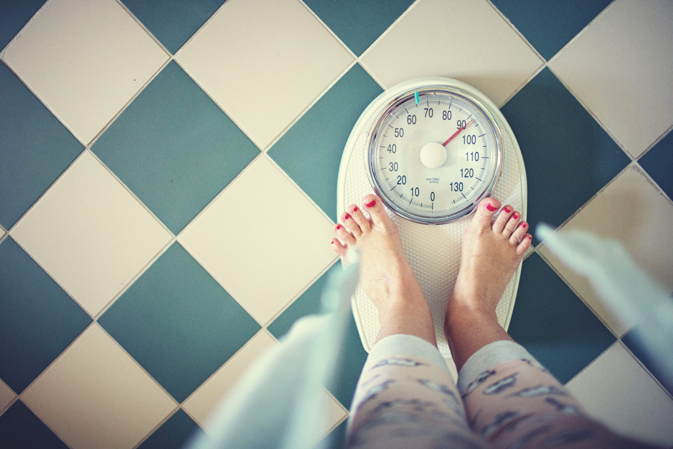 Eine Frau steht morgens im Badezimmer auf einer Waage.